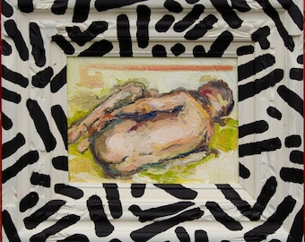 May include: Oil painting of a nude figure in a reclining pose, rendered with visible brushstrokes. The artwork is framed in a white frame with a black abstract pattern. The painting's colors include flesh tones, greens, and yellows.