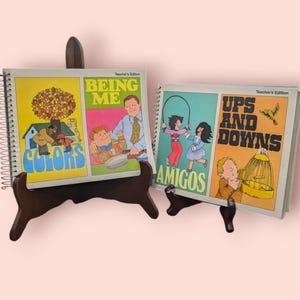 May include: Two spiral bound children's books with colorful illustrations. The first book is titled "Colors, Being Me" and the second book is titled "Amigos, Ups and Downs". Both books have the words "Teacher's Edition" printed on the cover.