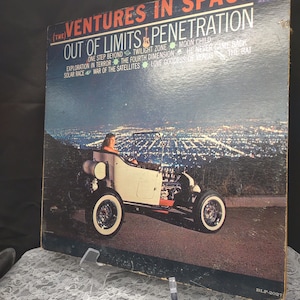 May include: A vintage vinyl record album cover featuring a hot rod car driving on a city street at night. The album title is "(The) Ventures in Space: Out of Limits Penetration" and lists the songs "One Step Beyond", "Twilight Zone", "Moon Child", "Exploration in Terror", "The Fourth Dimension", "He Never Came Back", "Solar Race", "War of the Satellites", "Love Goddess of Venus", and "The Bat". The album is by The Ventures and is on the Dolton Records label.