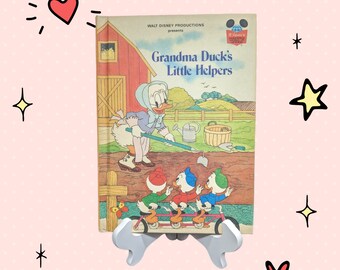 May include: A vintage children's book titled "Grandma Duck's Little Helpers" featuring a cartoon illustration of a duck family on the cover. The book is published by Walt Disney Productions.
