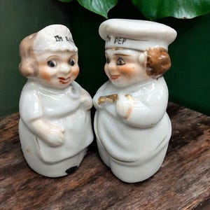 May include: A pair of vintage salt and pepper shakers shaped like chefs. The salt shaker is labeled "I'm Salt" and the pepper shaker is labeled "I'm Pep".