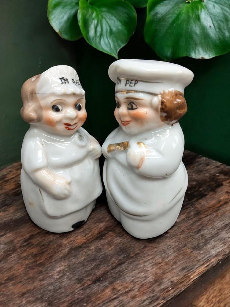 May include: A pair of vintage salt and pepper shakers shaped like chefs. The salt shaker is labeled "I'm Salt" and the pepper shaker is labeled "I'm Pep".