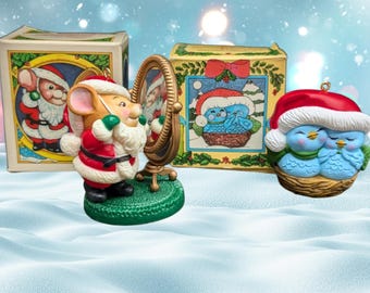 Könnte beinhalten: Drei Weihnachtsbaumschmuck: ein Blaumeisenpaar in einem Nest, eine Maus, die als Weihnachtsmann verkleidet ist und in einen Spiegel schaut, und eine Schachtel mit einer Zeichnung vom Weihnachtsmann und einer Maus.