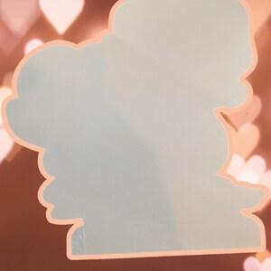 May include: A light blue sticker with a whimsical design featuring a cloud with a heart shape and a star. The sticker is outlined in a peach color.