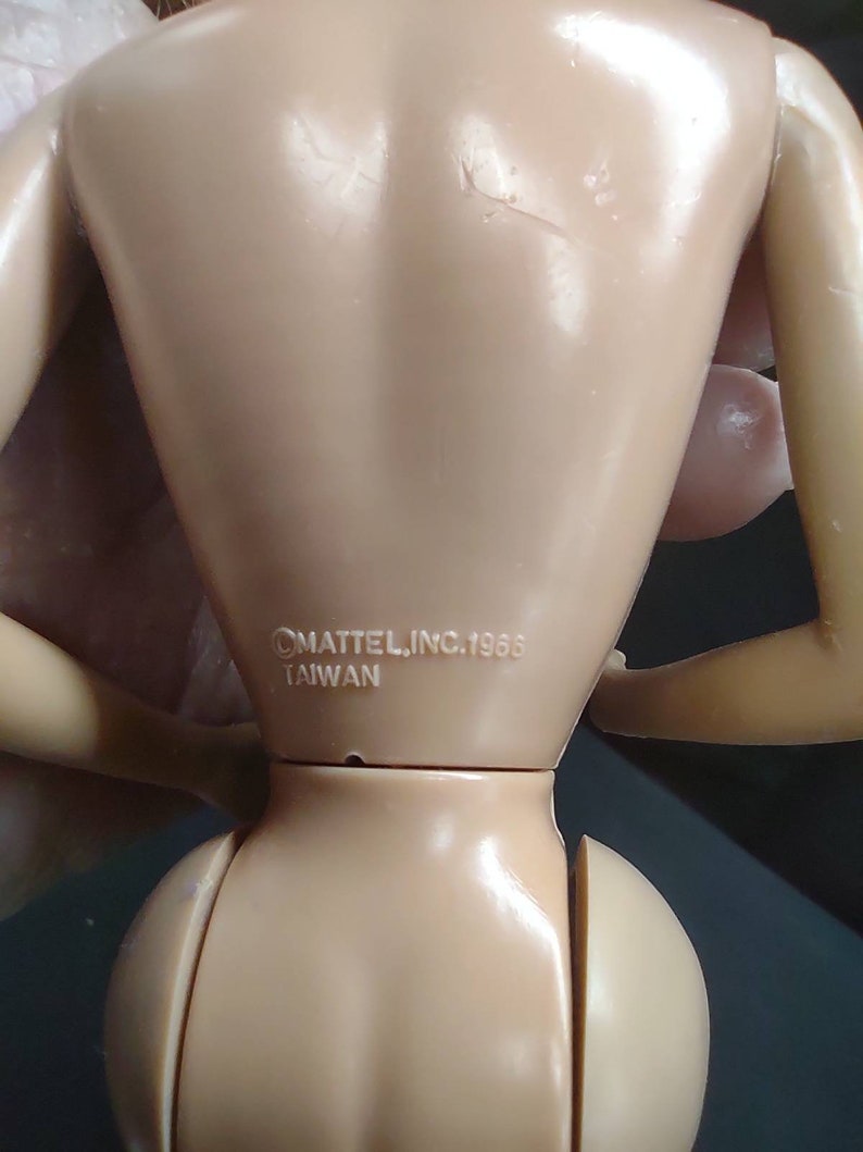 Peut inclure: Gros plan de l'arri&egrave;re d'une poup&eacute;e en plastique de couleur chair avec le texte "&copy;MATTEL, INC. 1988 TAIWAN" imprim&eacute; sur le bas du dos.