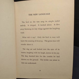 May include: Open book page with text titled "THE NEW LANGUAGE". The text describes a bird singing, chirping, and flying, followed by a dog's actions. Page number 9 is visible at the bottom.