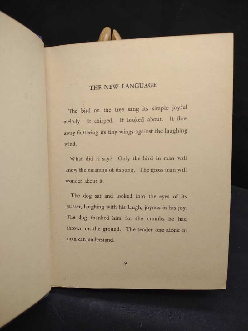 May include: Open book page with text titled "THE NEW LANGUAGE". The text describes a bird singing, chirping, and flying, followed by a dog's actions. Page number 9 is visible at the bottom.