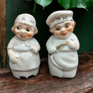 May include: A pair of vintage salt and pepper shakers shaped like chefs. The salt shaker is labeled "I'm Salt" and the pepper shaker is labeled "I'm Pep".