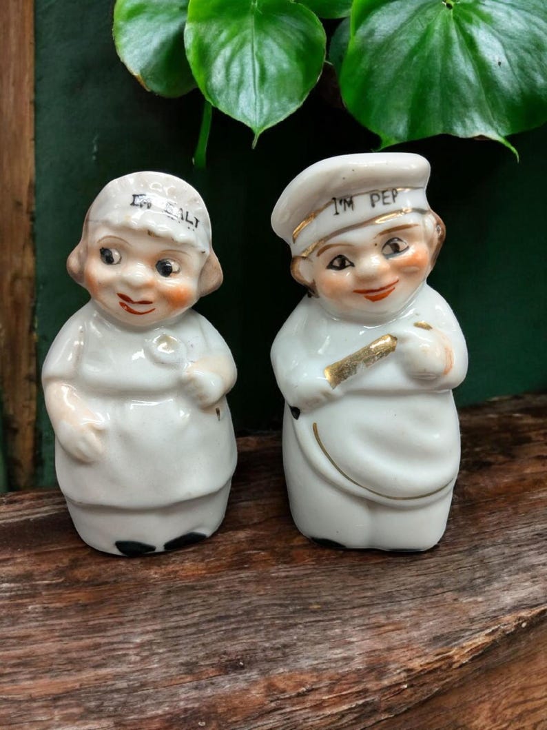 May include: A pair of vintage salt and pepper shakers shaped like chefs. The salt shaker is labeled "I'm Salt" and the pepper shaker is labeled "I'm Pep".