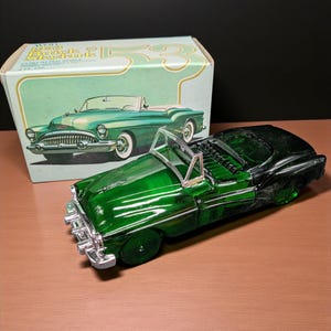May include: A green vintage car-shaped bottle with chrome accents and a matching box. The box features an illustration of the car and the text "Avon Buick Skylark 53". The car is a classic convertible design.