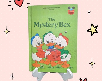 May include: A green book with the title "The Mystery Box" and a picture of three ducklings looking at a gift box that says "Do not open!" The book is from Walt Disney Productions.