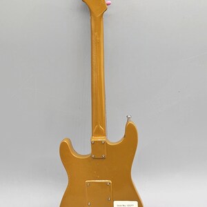 May include: Gold-colored electric guitar figurine with pink tuning pegs. The back of the figurine has a label with the text "Item No. 12077 Flower Power Figurine" and a barcode.