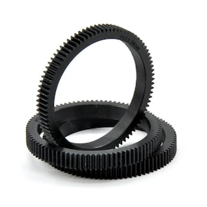 Op de afbeelding: Drie zwarte plastic tandwielen die op elkaar gestapeld zijn. De bovenste ring heeft de tekst "FLEX 59mm" erop gedrukt.