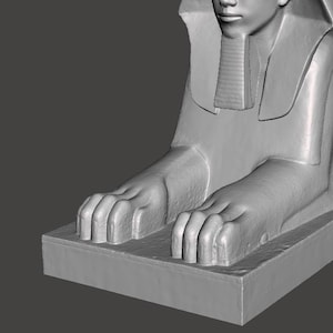 Peut inclure: Une sculpture en pierre grise représentant un sphinx avec une tête humaine et un corps de lion. Le sphinx est couché, la tête tournée sur le côté. La sculpture est détaillée et réaliste.