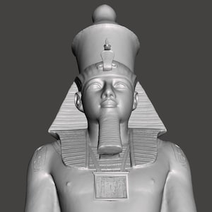 Puede incluir: Una escultura de piedra gris de un faraón egipcio que lleva un alto tocado con un diseño decorativo. El faraón tiene barba y un collar con un colgante rectangular.