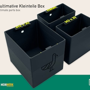 Puede incluir: Tres cajas de almacenamiento de plástico negro con etiquetas para "M5 x 30", "M3 x 30" y "Haken". Las cajas están diseñadas para organizar piezas pequeñas y forman parte de un sistema llamado "Die ultimative Kleinteile Box".