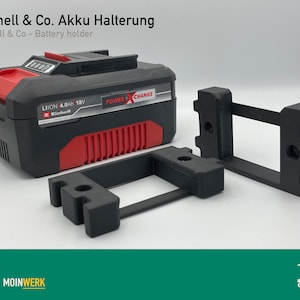 Könnte beinhalten: Ein schwarzer Kunststoff-Akkukorb für Einhell Elektrowerkzeuge. Der Halter besteht aus zwei Teilen, einem mit einer rechteckigen Öffnung und einem mit einer kleineren Öffnung. Der Halter ist für einen roten und schwarzen Einhell Akku mit dem Aufdruck "LIION 4.0Ah 18V Einhell POWER CHANGE" ausgelegt.