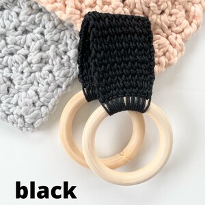 Puede incluir: Bucle de crochet negro unido a dos anillos de madera. Los anillos tienen un di&aacute;metro de aproximadamente 10 cm. La palabra "negro" est&aacute; escrita debajo de los anillos.