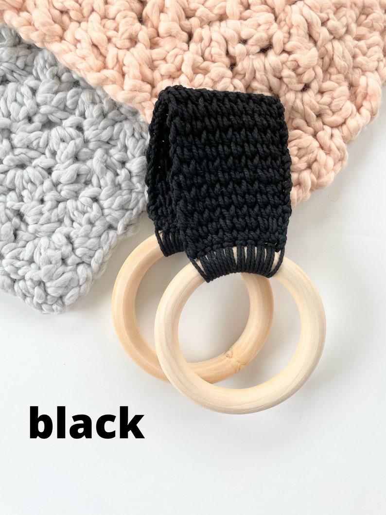 Puede incluir: Bucle de crochet negro unido a dos anillos de madera. Los anillos tienen un di&aacute;metro de aproximadamente 10 cm. La palabra "negro" est&aacute; escrita debajo de los anillos.