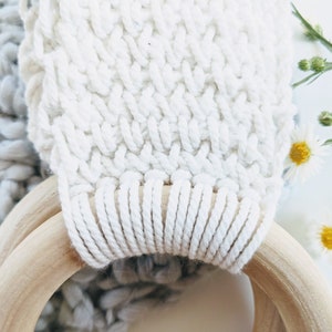 This picture shows a close up of the towel holder. the crocheted fabric is white and textured and the wooden ring is smooth and a shade of light brown