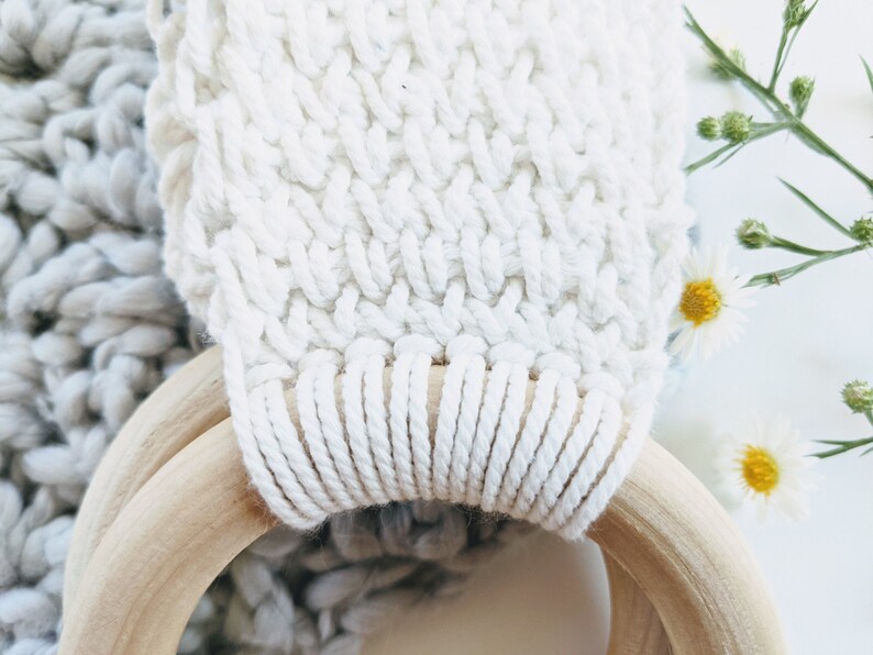 This picture shows a close up of the towel holder. the crocheted fabric is white and textured and the wooden ring is smooth and a shade of light brown