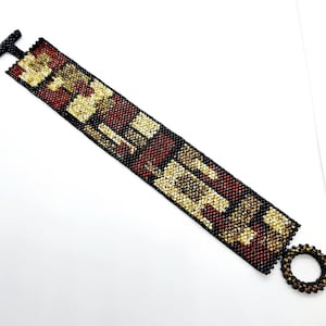 May include: A beaded bracelet with a geometric pattern in black, gold, and red. The bracelet has a toggle clasp.