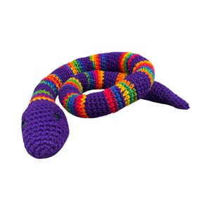 May include: A crocheted snake toy in a vibrant rainbow pattern with a purple head and body. The snake's body is striped with bands of red, orange, yellow, green, and blue. The toy is made of soft yarn and has small black eyes.