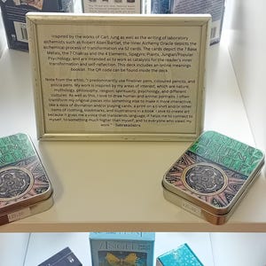 Puede incluir: Dos barajas de cartas de juego verdes y doradas con un dise&ntilde;o en blanco y negro en la parte delantera. Las barajas est&aacute;n en un estante blanco con otras barajas de cartas de juego. Una descripci&oacute;n enmarcada de las barajas est&aacute; encima de las barajas.