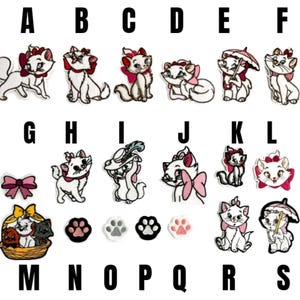 Puede incluir: Parches bordados con un gato blanco con un lazo rosa en varias poses. Otros parches incluyen un lazo rosa, huellas de patas de gato y una cesta con gatos. Letras de la A a la S.