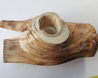 Puede incluir: Una pieza de madera natural con un gran agujero en el centro. La madera es de color marrón claro con vetas marrones más oscuras. La pieza tiene forma de media luna.