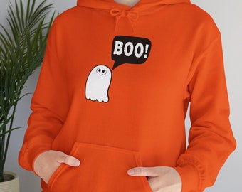 May include: Orange hooded sweatshirt with a front pocket. A white ghost graphic with the word "BOO!" in a black speech bubble is printed on the front. The sweatshirt has a drawstring hood and long sleeves.