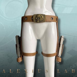 Puede incluir: Una taza de cerámica blanca con asa negra y el texto "But First, Coffee" en negrita negra. La taza se encuentra sobre un fondo borroso, resaltando su diseño sencillo.