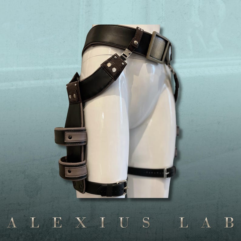 May include: A black leather and brown suede harness with silver-tone hardware. The harness features a wide belt, adjustable straps, and multiple loops. The text "ALEXIUS LAB" is at the bottom of the image.