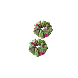 May include: Two green scrunchies with a floral pattern in pink and white. The scrunchies are made of a soft, silky fabric and are perfect for adding a pop of color to any hairstyle. These hair accessories are a stylish addition to any collection.