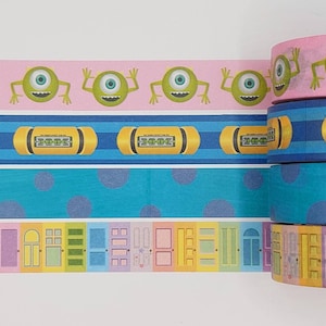 Puede incluir: Cuatro rollos de cinta washi con temática de Monsters Inc. El rollo superior tiene un fondo rosa con monstruos verdes de un ojo. El segundo rollo tiene un fondo a rayas azul y blanco con cápsulas amarillas que dicen "2001". El tercer rollo tiene un fondo azul con lunares blancos. El rollo inferior tiene un fondo blanco con puertas de colores.