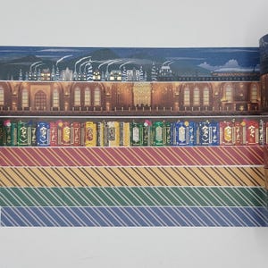 Puede incluir: Un conjunto de cinco cintas washi con una escena del castillo de Hogwarts, una fila de libros y cuatro patrones de rayas diferentes en rojo, dorado, verde y azul.