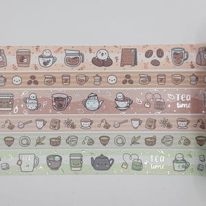 Puede incluir: Rollos de cinta adhesiva washi decorativa con ilustraciones temáticas de té y café. Los diseños incluyen tazas de café, tazas de té, teteras, granos de café y personajes sonrientes. La paleta de colores incluye tonos de marrón, rosa y verde.