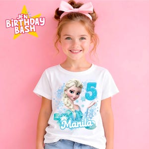 May include: White t-shirt featuring a graphic of Elsa from Frozen, with the number 5 and the name "Manila" in blue. The shirt has a light blue bow and snowflake design. The text "Jen Birthday Bash" is in the upper left corner.