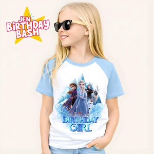May include: A white and light blue raglan t-shirt featuring a graphic of characters from the movie Frozen, with the text "BIRTHDAY GIRL". The shirt is worn by a young girl wearing sunglasses. The text "JEN BIRTHDAY BASH" is also visible.