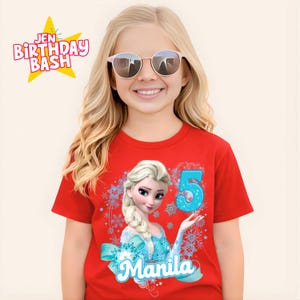 May include: A red t-shirt featuring a graphic of Elsa from Frozen, the number 5, and the name "Manila" in a blue font. The shirt also has a snowflake design. The text "Jen Birthday Bash" is in the upper left corner.