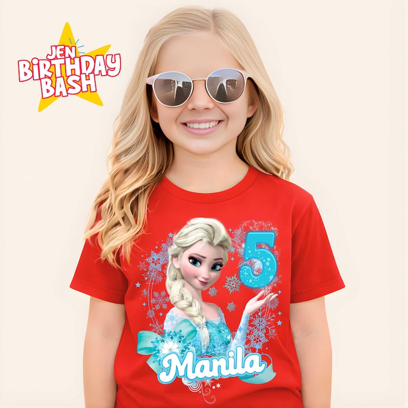 May include: A red t-shirt featuring a graphic of Elsa from Frozen, the number 5, and the name "Manila" in a blue font. The shirt also has a snowflake design. The text "Jen Birthday Bash" is in the upper left corner.