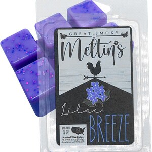 May include: A package of purple scented wax cubes with glitter. The label reads "Great Smoky Meltin's Lilac Breeze" with a rooster and floral design. The package contains 2.5oz (70.9g) of wax cubes.