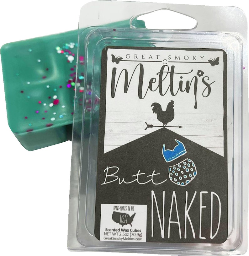 May include: A teal blue scented wax cube with pink and white glitter. The wax cube is packaged in a clear plastic container with a label that reads "Great Smoky Meltin's Butt Naked" with a rooster illustration. The label also includes the text "Hand-poured in the USA, Scented Wax Cubes, Net Wt 2.5oz (70.9g), GreatSmokyMeltins.com".