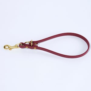May include: A burgundy leather dog lead with a gold metal clip.
