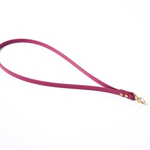 May include: A burgundy leather strap with a gold metal clasp. The strap has two gold metal rivets.