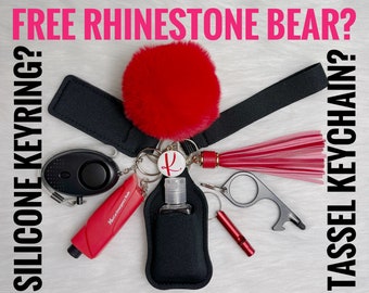 May include: An assortment of keychain accessories, including a red pom-pom, a black wrist strap, a personal alarm, a red emergency tool, a bottle holder, a bottle opener, and a whistle. The image includes the text "FREE RHINESTONE BEAR?" and "SILICONE KEYRING?" and "TASSEL KEYCHAIN?"