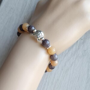 May include: A bracelet with brown and yellow beads and a silver cat charm.