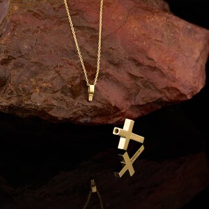 May include: A gold chain necklace with a small cross pendant. The cross has the name "Jesica" engraved on it.