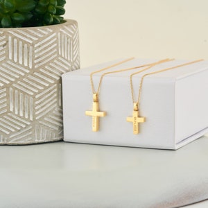 May include: Two gold cross necklaces on a white box. One cross is engraved with the name "Jessica" and the other with the date "03.13.2020".