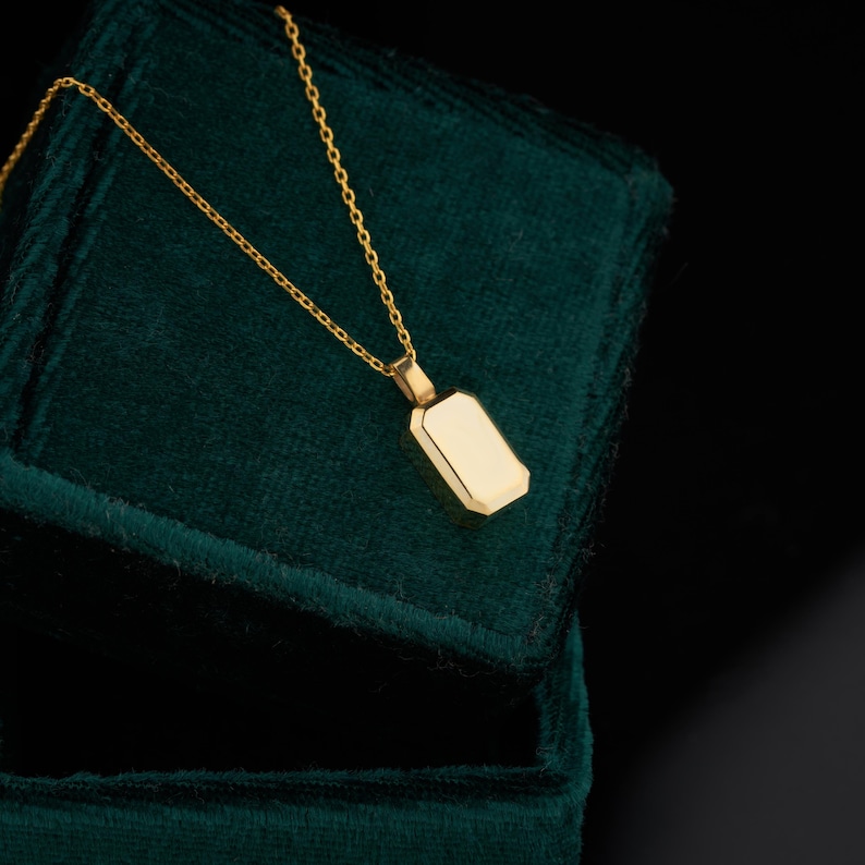 Peut inclure: Un collier en or avec un pendentif rectangulaire, reposant sur un &eacute;crin en velours vert fonc&eacute;.